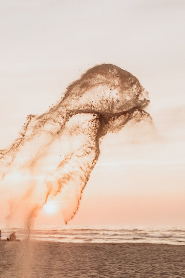 Burst Of Fine Sand In The Air Near Body Of Water