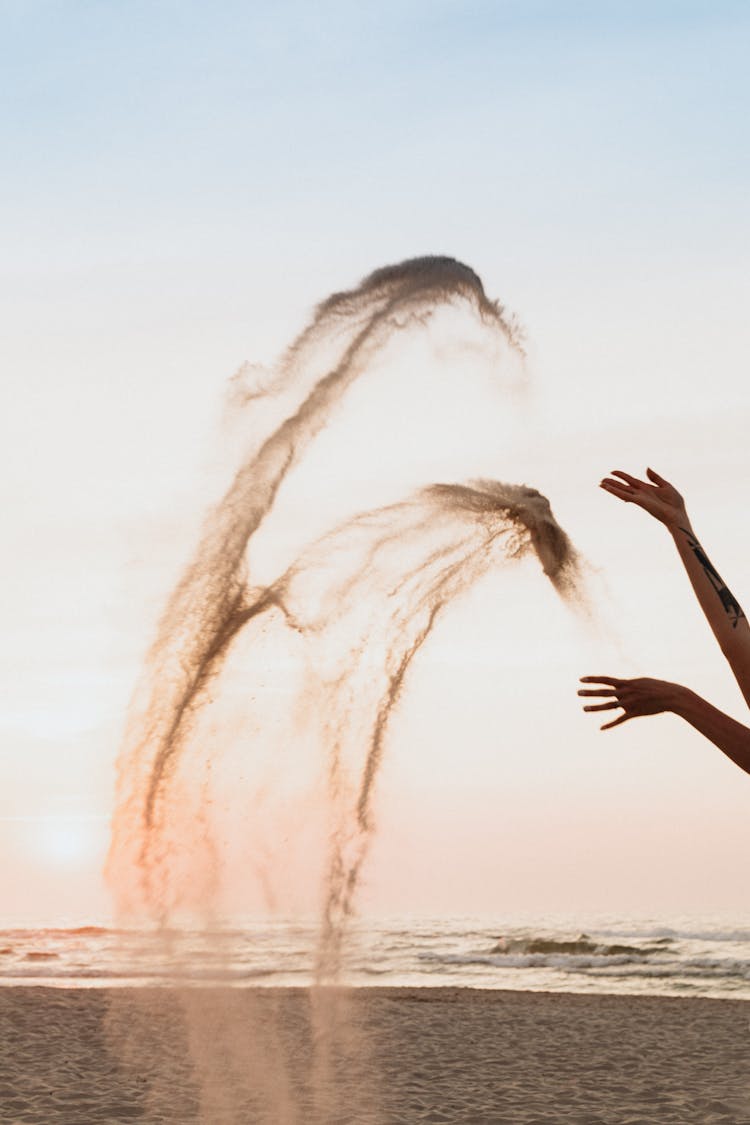 Hands Of A Person Splashing Sand In Air