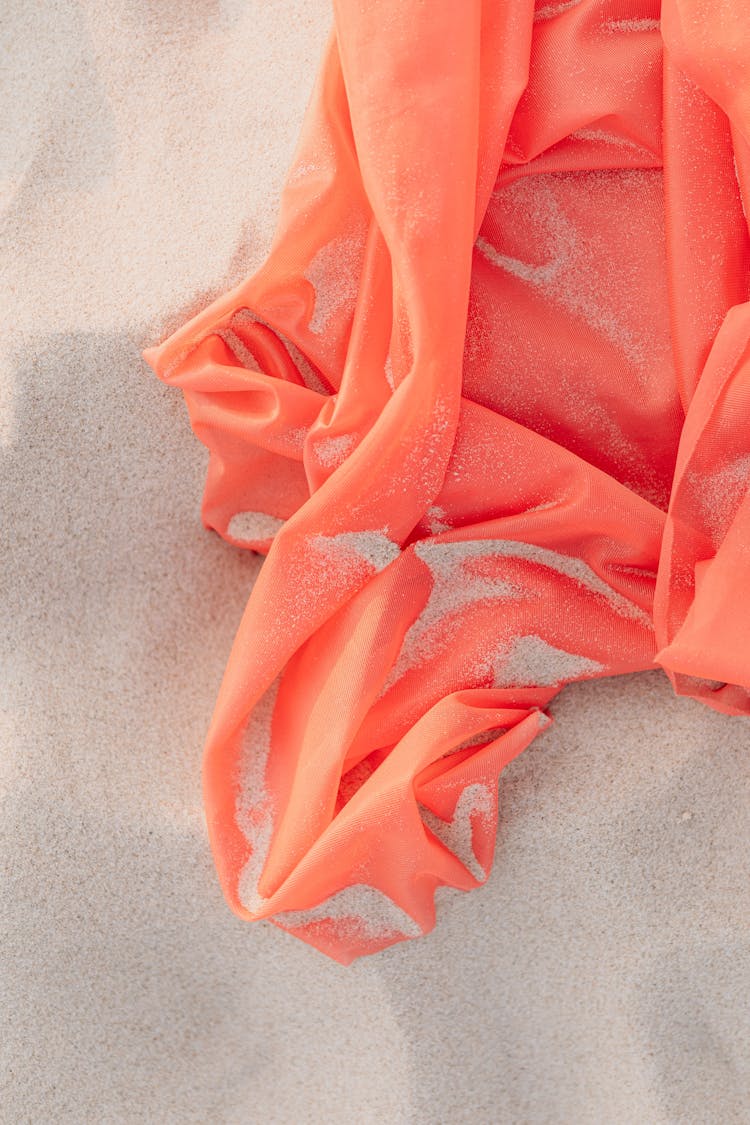 Crinkled Orange Textile On Fine Sand