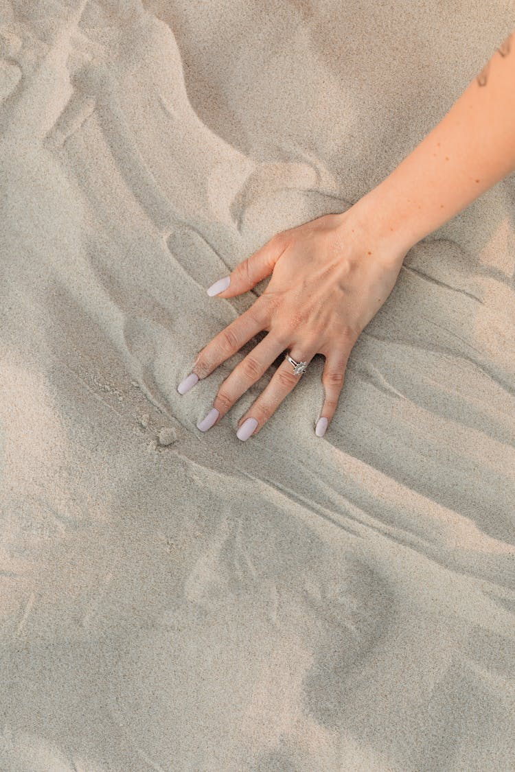 Persons Left Hand On Sand