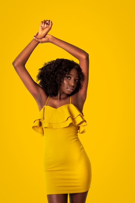 Elegant portrait of an African American woman in a yellow dress posing against a matching background.