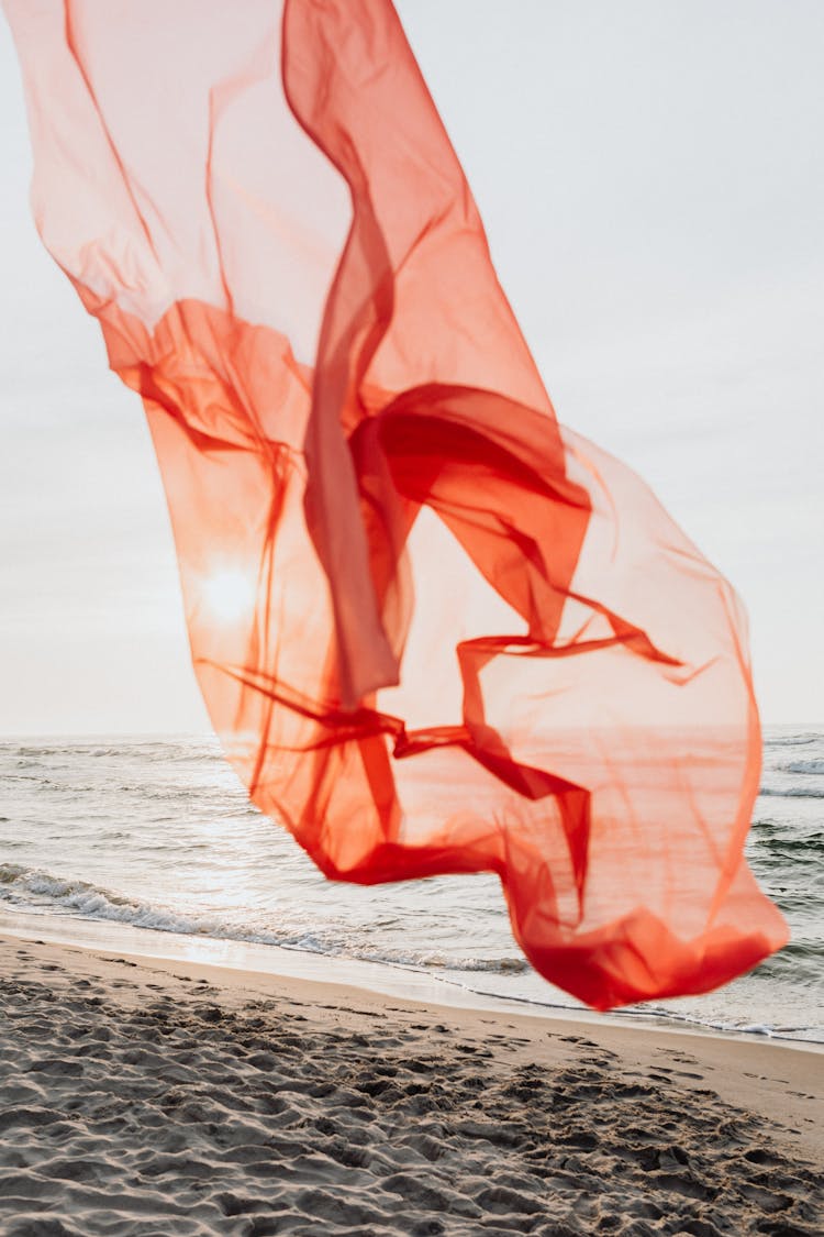 Orange Sheer Fabric Blown By Wind At Beach Shore