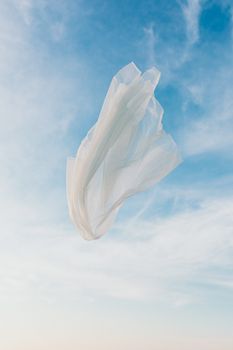 半透明的白色织物在充满活力的蓝天上优雅地漂浮