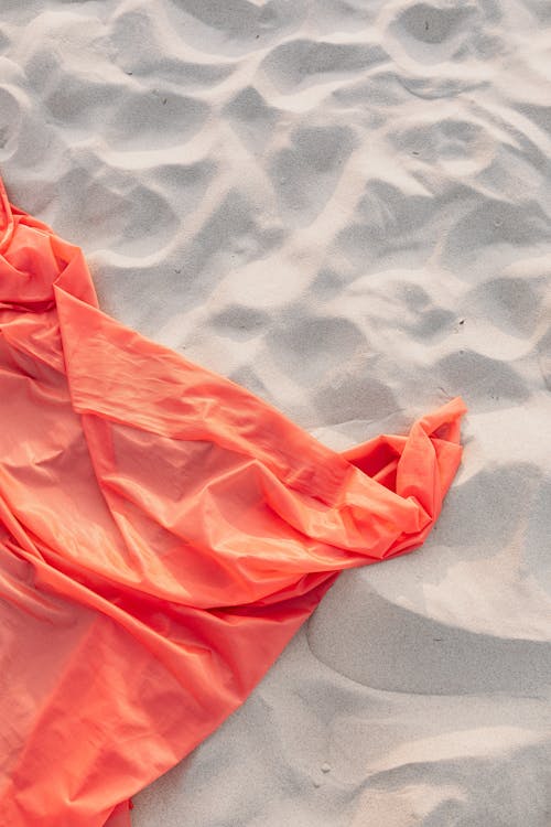 Free Sheet of Orange Textile on White Sand Stock Photo