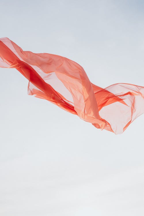 Wind Blowing on Orange Sheer Fabric Under Blue Sky