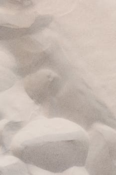 Abstract close-up of textured sand and rocks, highlighting natural patterns and surfaces.