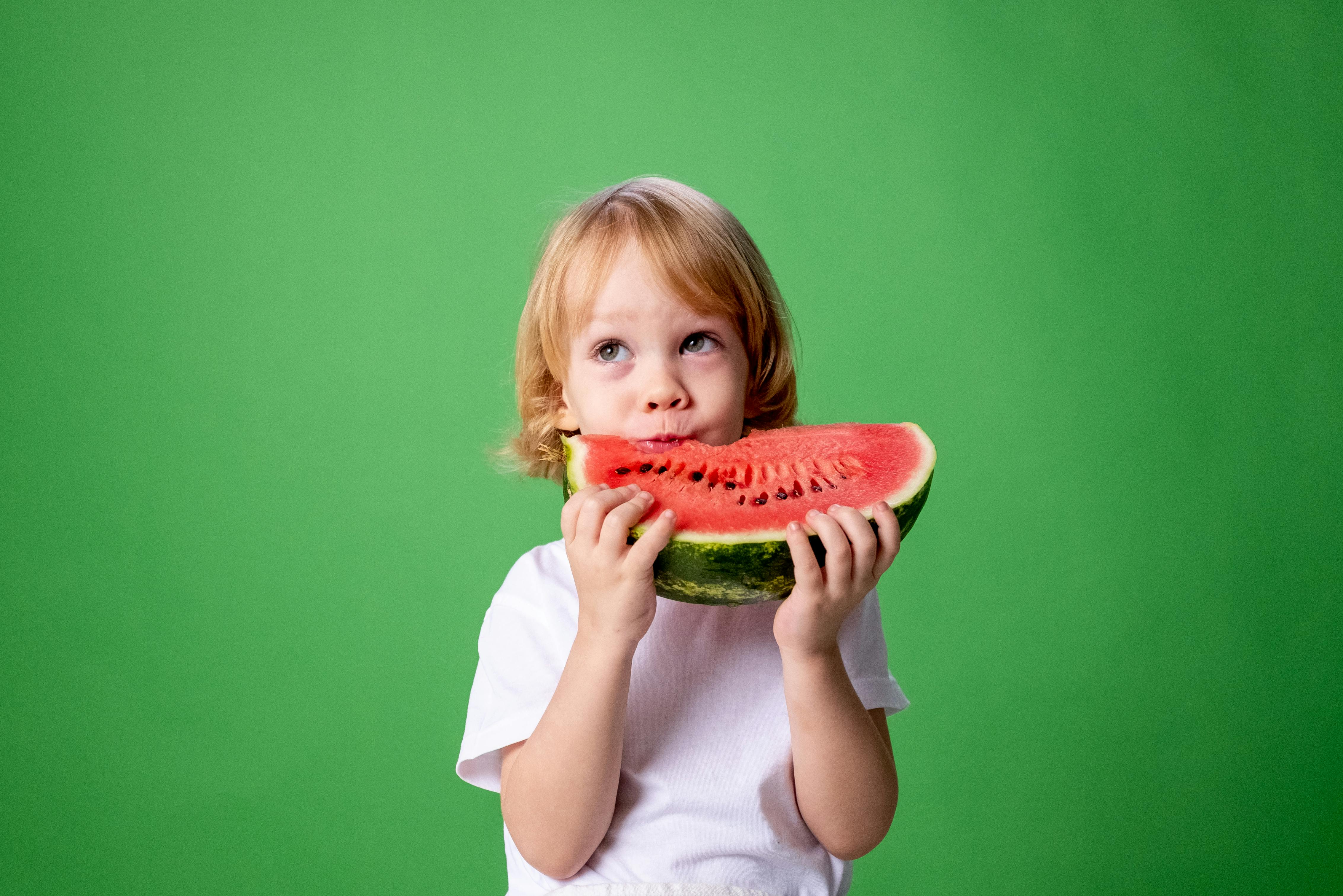 girl in white long sleeve shirt eating watermelon