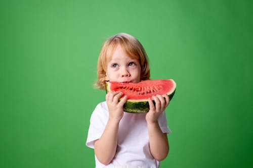 Free Girl in White Long Sleeve Shirt Eating Watermelon Stock Photo
