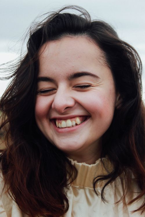 Free Close-up portrait of a joyful woman with brown hair, smiling outdoors in Prague. Captures happiness candidly. Stock Photo