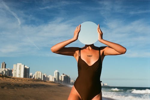 A Woman in Black One Piece Swimsuit Holding a Mirror