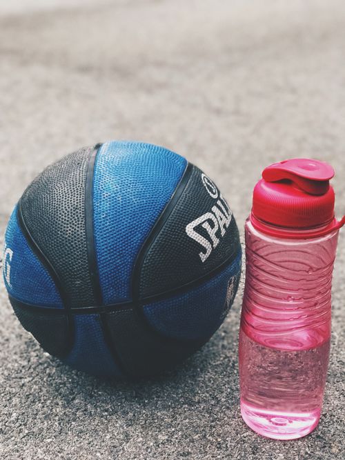 Free A blue basketball and a red water bottle on an outdoor court, symbolizing sports and hydration. Stock Photo