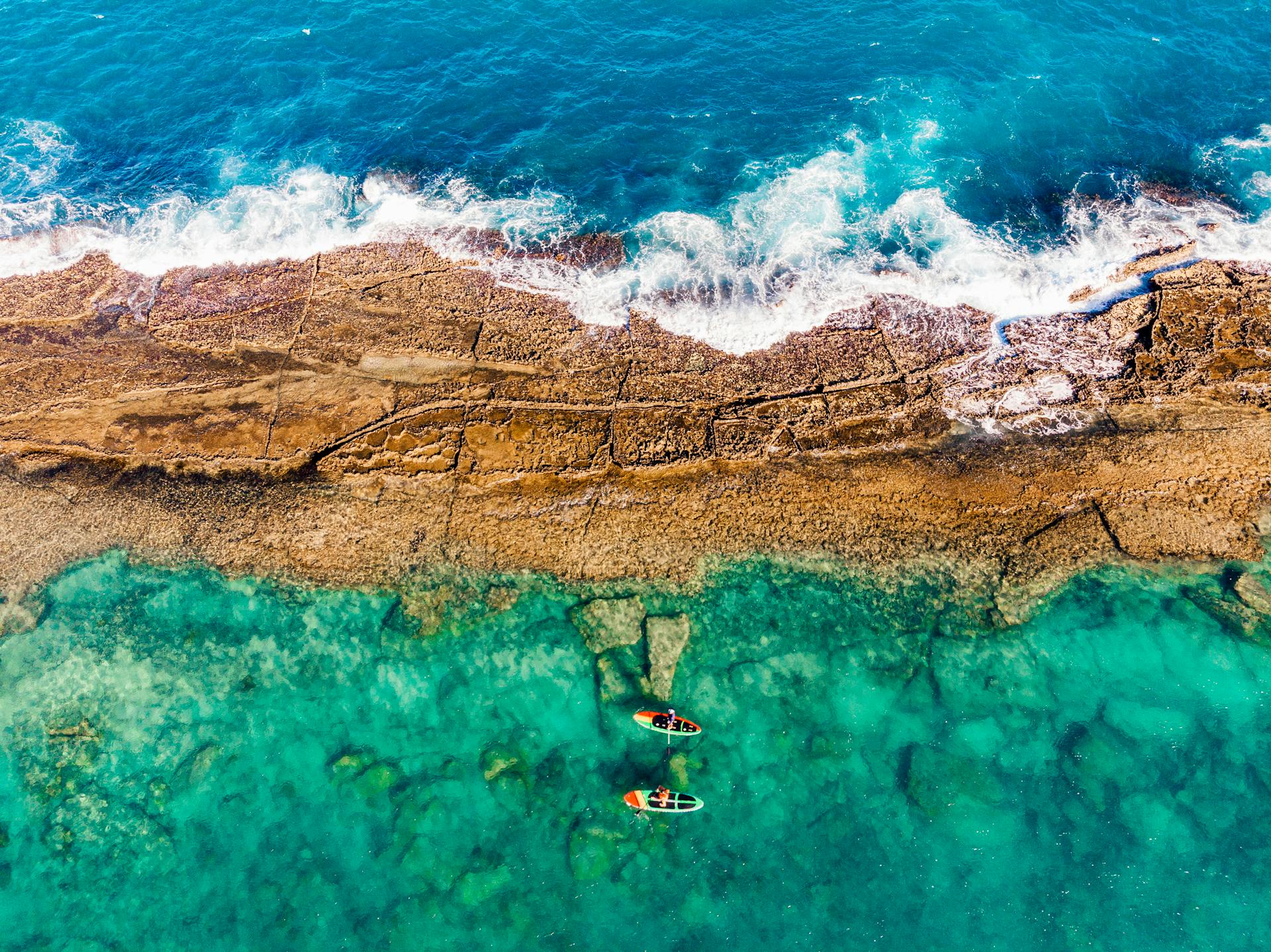 Aerial shot of paddle boarders navigating the crystal-clear waters off the Brazil coast, showcasing vibrant marine textures.