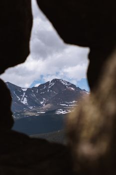 A breathtaking view of the Rocky Mountains framed by a natural rock formation in Estes Park, Colorado.