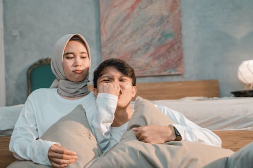 Free Woman Wearing Hijab Sitting Beside Man Holding a Pillow Stock Photo
