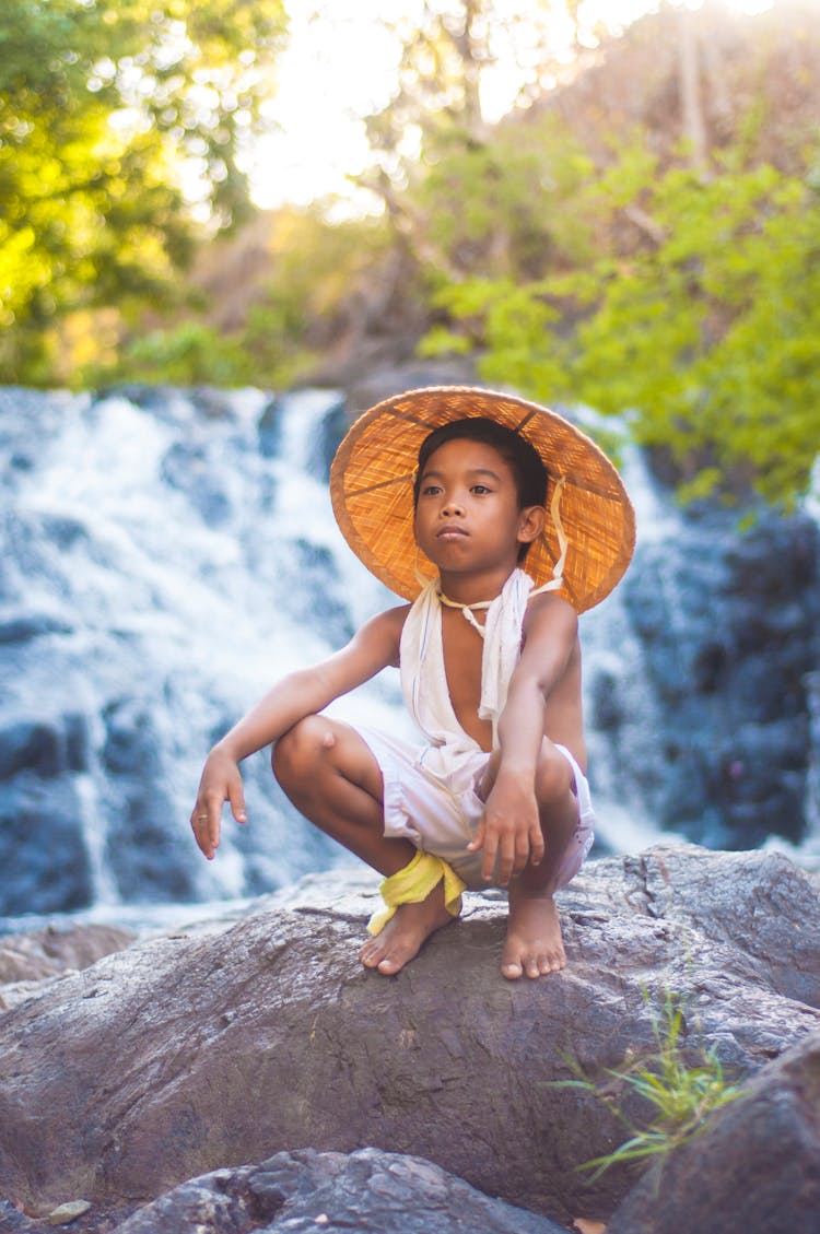 Child Wearing A Hat Sitting On A Rock