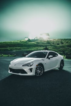 Sparkling stylish new automobile standing near green field in bright harsh light of village