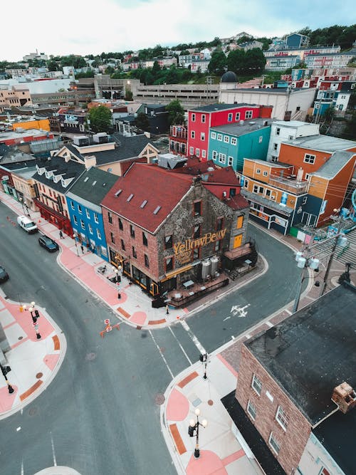 From above of asphalt roadway near aged residential building facades with bright walls under sky in city