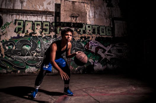 Young man dribbling a basketball on a graffiti-covered court, showcasing street sport style.
