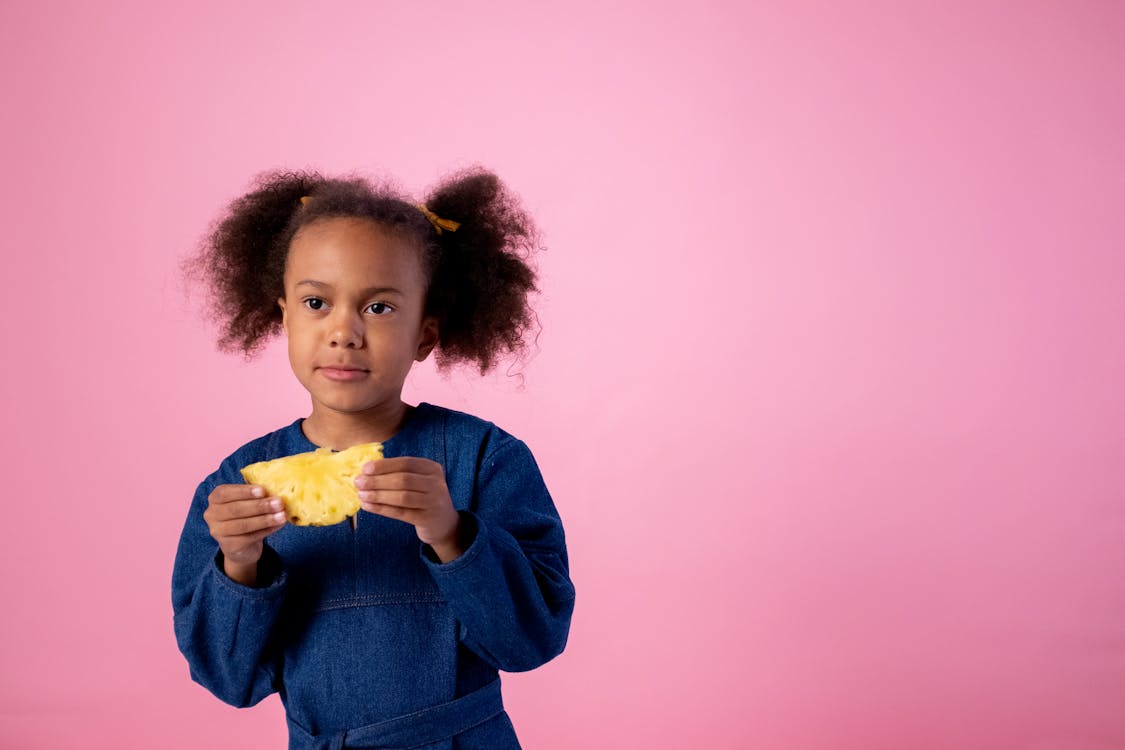 Girl in Blue Long Sleeve Shirt Holding Yellow Flower