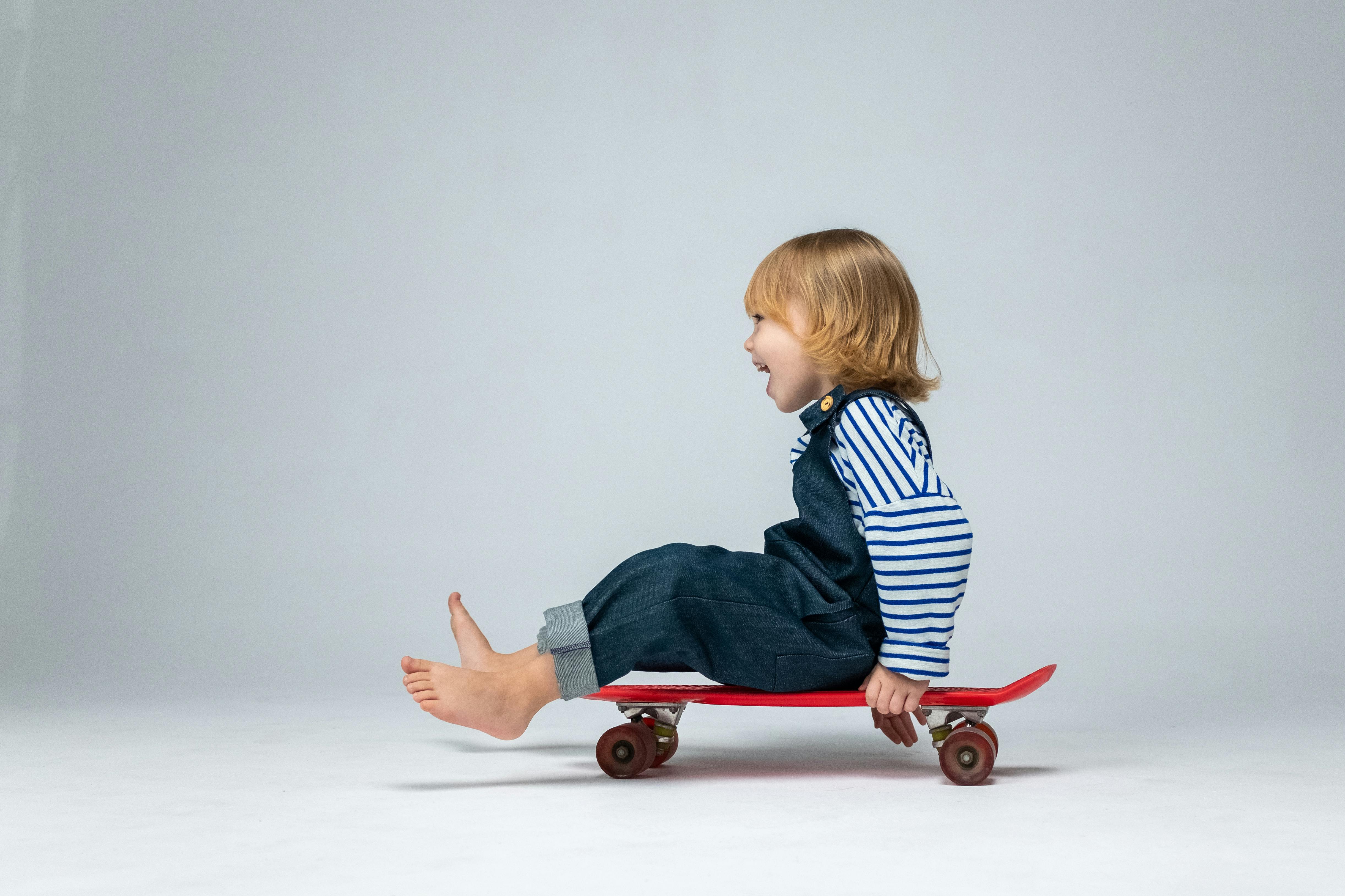 child in blue and white striped shirt sitting on red wooden chair