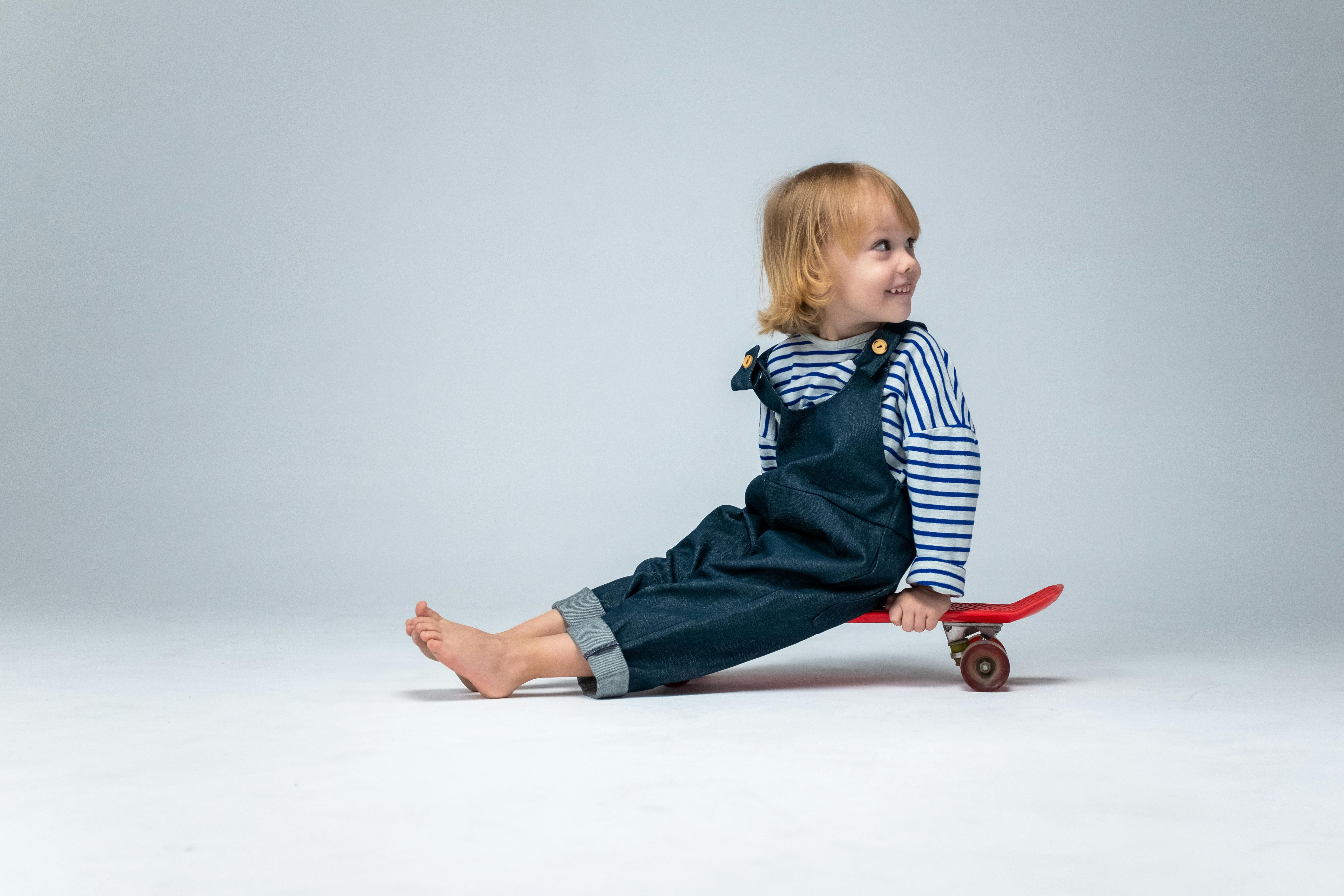 boy in blue and white striped shirt and blue denim jeans sitting on red wooden chair