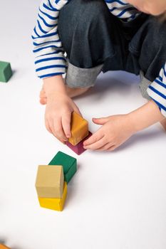 年幼的孩子在白色背景下创意地玩彩色积木