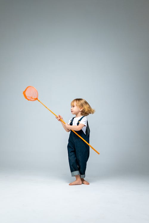 Girl in Blue Long Sleeve Shirt Holding Orange and Black Basketball Hoop