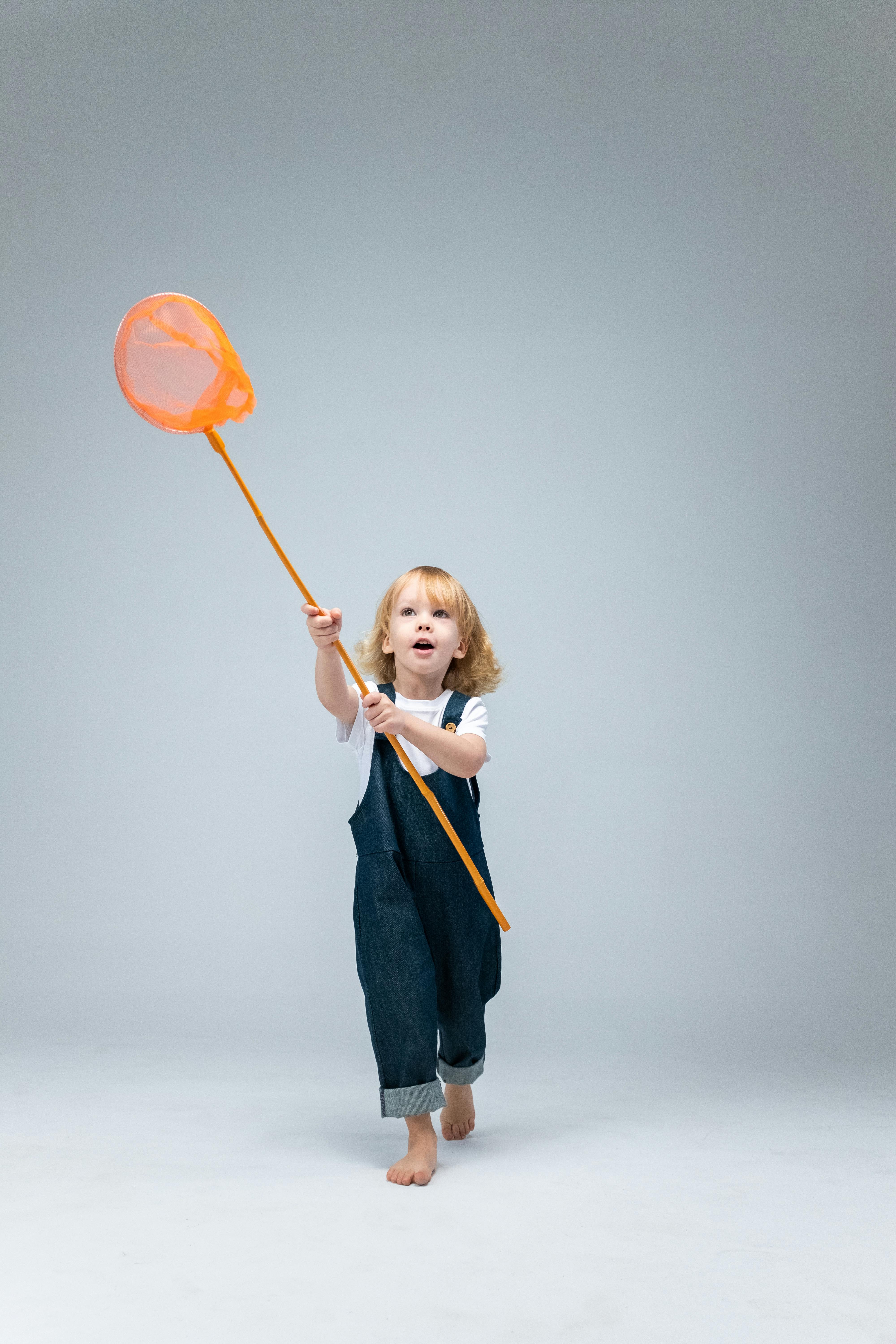 girl in blue denim dungaree holding orange balloon