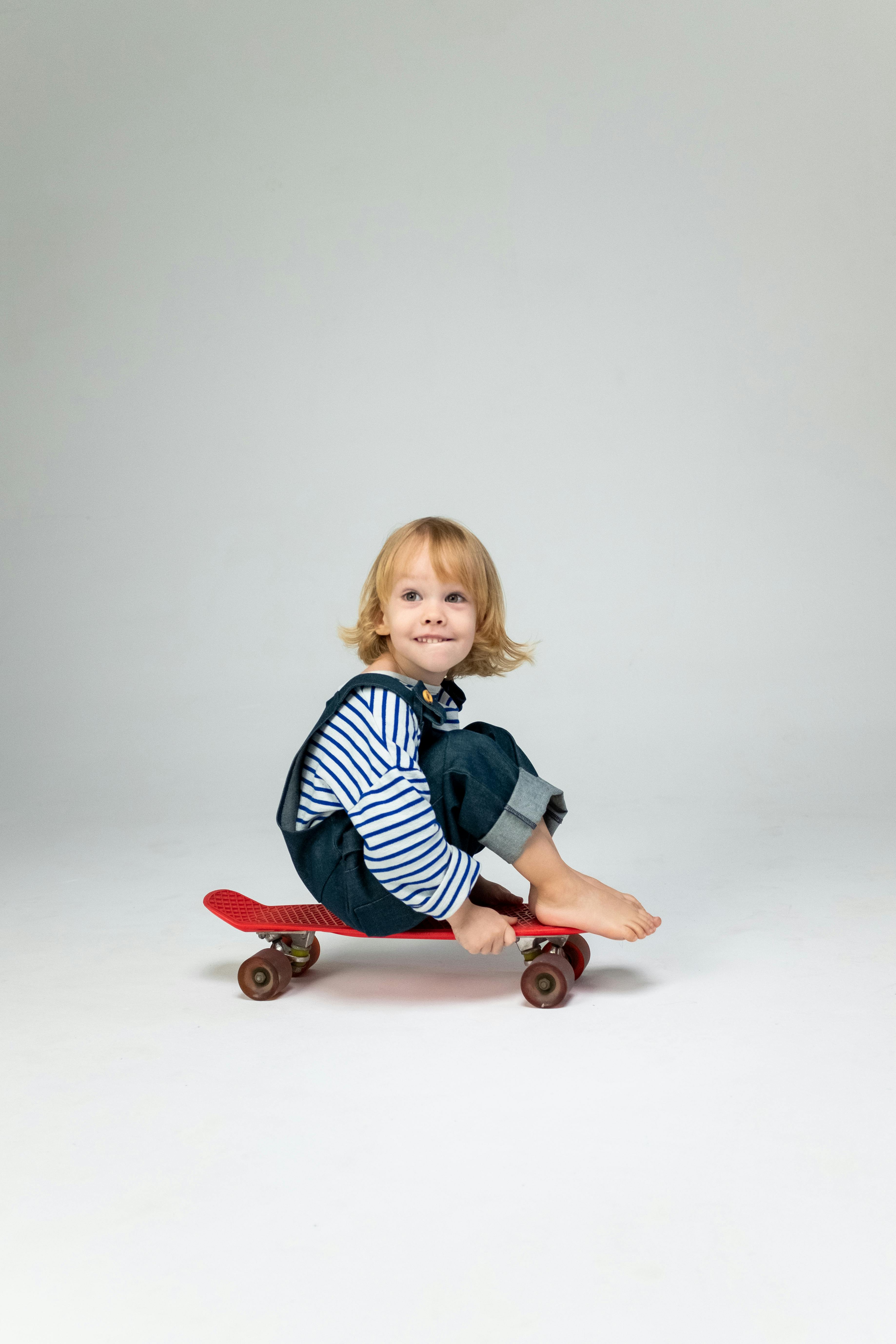 girl in blue and white striped long sleeve shirt sitting on red and white plastic ride