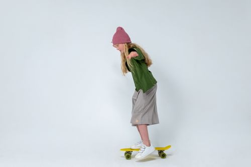 Free Young girl practicing skateboarding indoors, wearing a pink hat on a white background. Stock Photo
