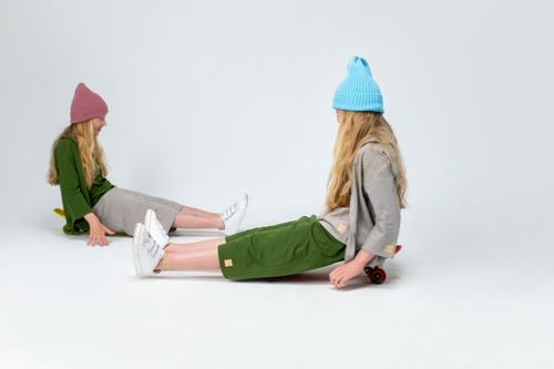 Free Two girls wearing colorful hats enjoy skateboarding indoors against a white background. Stock Photo