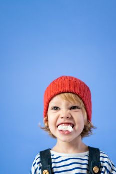 一个戴着红色帽子的可爱金发孩子，表情有趣，背景是蓝色的