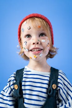 在工作室的蓝色背景前，快乐的孩子戴着红色帽子和贴纸，表达着喜悦