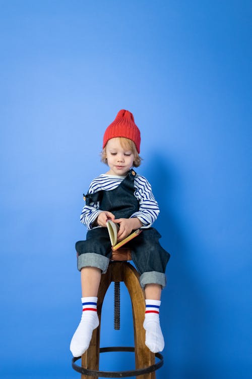 Boy in Black and White Striped Long Sleeve Shirt and Blue Denim Shorts Sitting on Brown