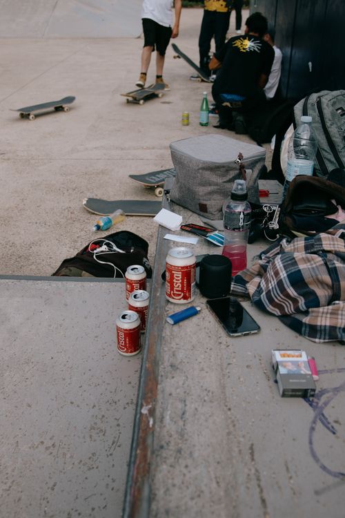Free From above of clothes mobile phone and bottles on concrete steps of skate park with people on skateboards Stock Photo
