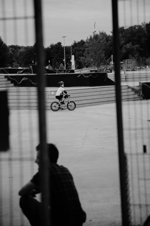 Free Black and white of child in helmet riding bike in modern skate park Stock Photo