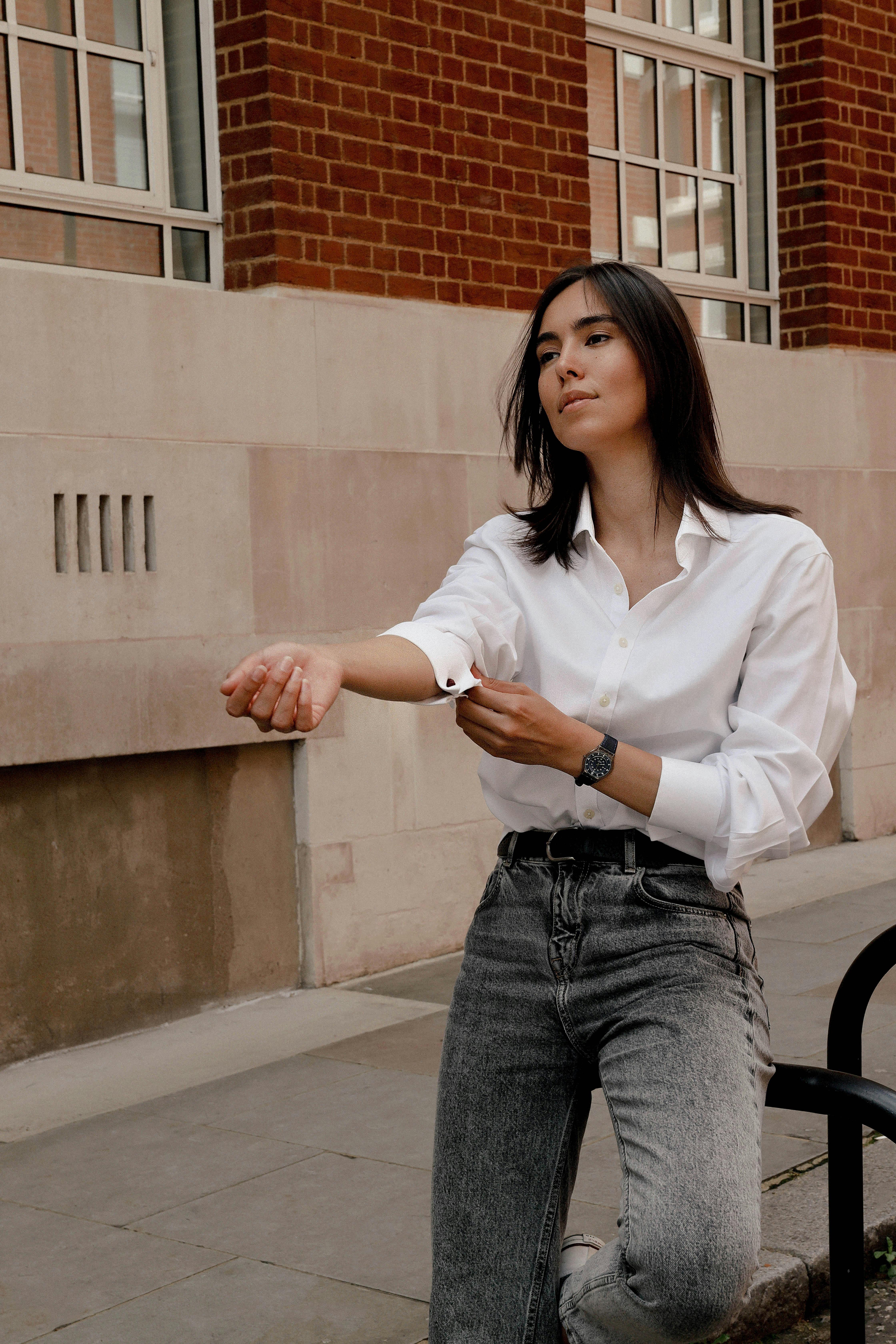 Woman In White Dress Shirt And Blue Denim Jeans Sitting On Black Chair Free Stock Photo