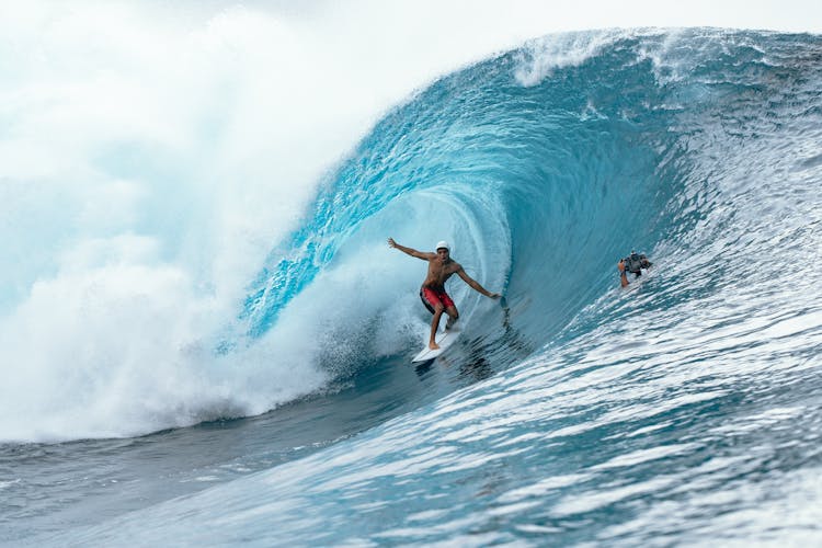 Surfer Riding Under Crest Of Wave