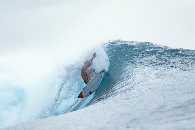 Person Riding On Surfboard On Wave