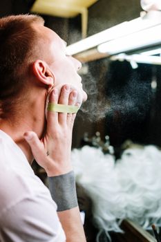 A man applying makeup in a dressing room, showcasing transformation and identity through cosmetics.
