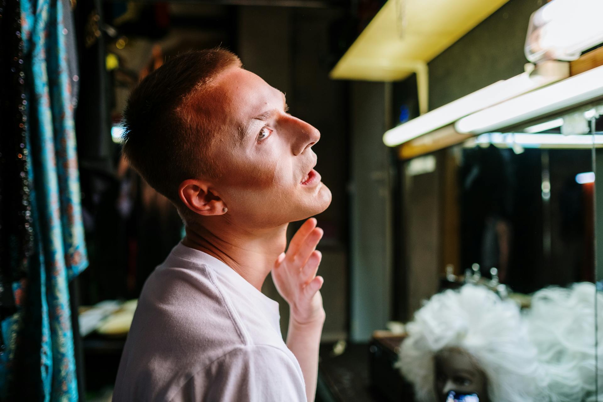 A drag artist capturing a moment of transformation in a theatre dressing room, applying makeup.