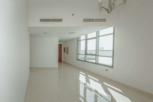 Bright and empty modern apartment interior with large windows and polished floors.