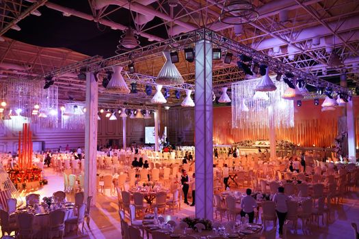 A grand indoor wedding reception with ornate lighting, tables, and a vibrant atmosphere.