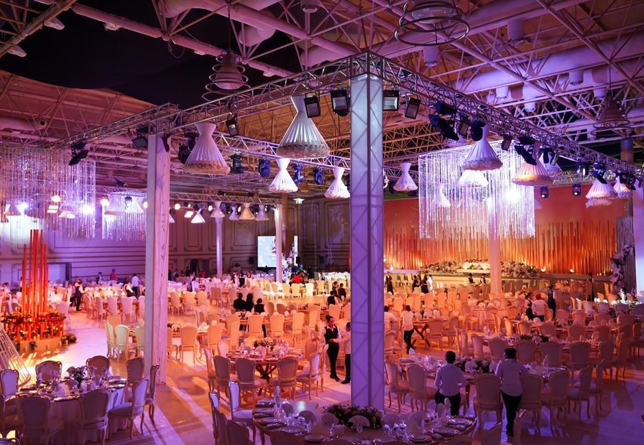 A grand indoor wedding reception with ornate lighting, tables, and a vibrant atmosphere.