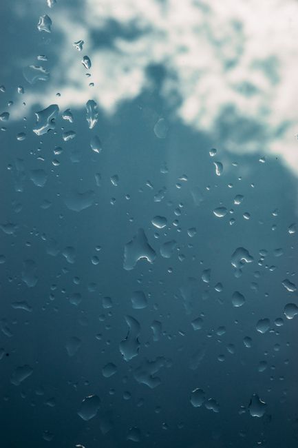 Close-up of raindrops on glass, capturing texture and mood of a rainy day.