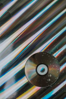 Shimmering colourful compact disk with drops of liquid on holographic background through glass — photo by lil artsy