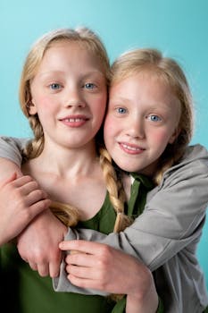 一对迷人的双胞胎姐妹肖像，金发辫在碧绿色背景下相拥