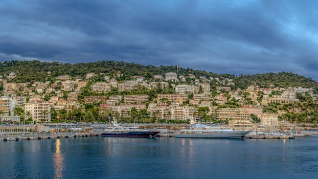Beautiful view of Nice harbor in France with luxury yachts against a mountainous backdrop.