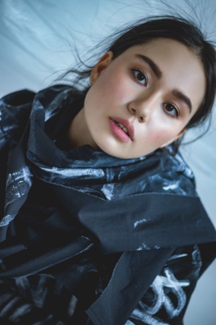 From above of young ethnic female with makeup and brown eyes looking at camera on light background