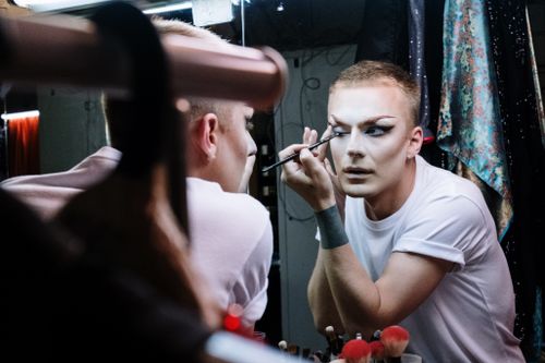 Free A drag queen skillfully applies makeup in front of a mirror in a dressing room. Stock Photo